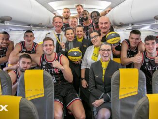 Jugadores del Bilbao Basket junto a la tripulación de Vueling celebrando la renovación del patrocinio para la temporada 2024/25 dentro de un avión de la aerolínea.