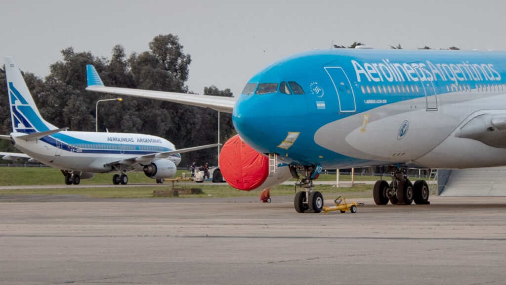 Aerolíneas Argentinas reduce pérdidas y reporta superávit operativo en 2024 Aviones de Aerolíneas Argentinas en plataforma, destacando un Airbus A330-200 y un Boeing 737-700 con livery retro
