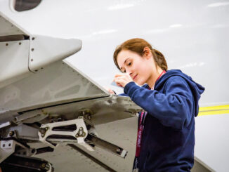 Técnica aeronáutica trabajando en mantenimiento de aeronave tras nueva normativa de ANAC para la importación de piezas aeronáuticas
