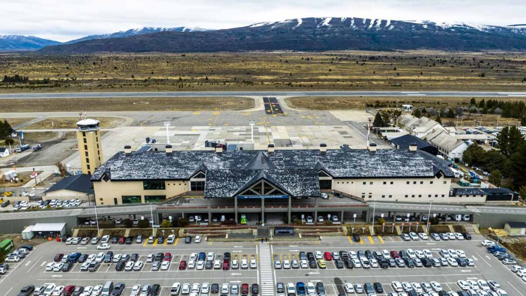 Nuevo servicio FBO para vuelos privados en el Aeropuerto de Bariloche durante la temporada invernal Vista aérea del Aeropuerto de Bariloche con nieve en invierno y gran cantidad de vehículos en el estacionamiento