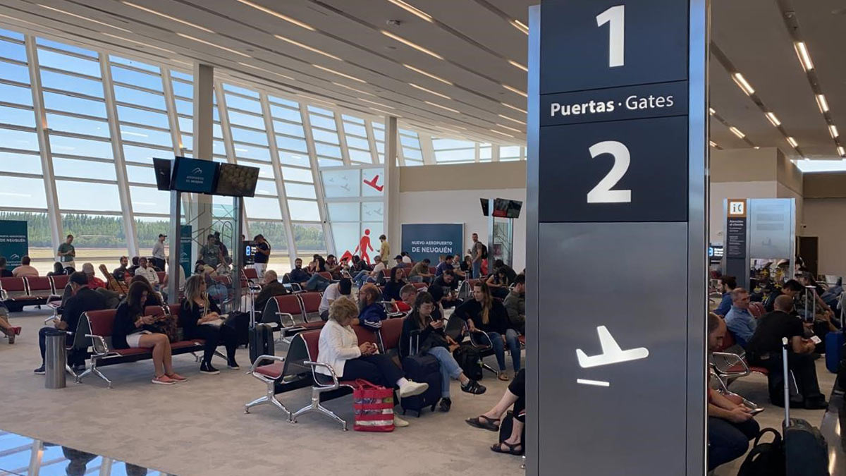 LATAM reanudará sus vuelos entre Neuquén y Santiago de Chile Sala de embarque del aeropuerto de Neuquén con pasajeros esperando en las puertas 1 y 2