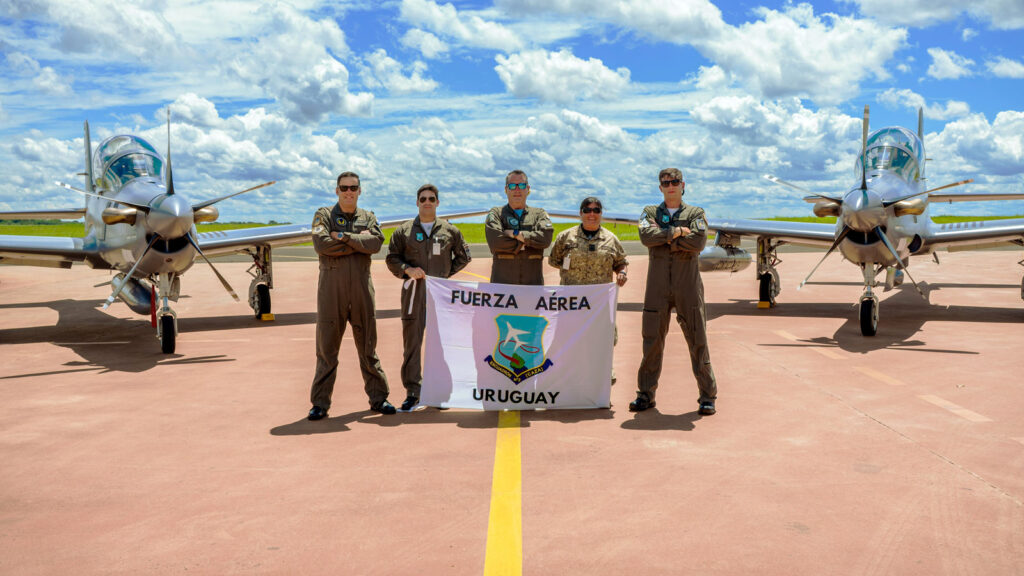 La Fuerza Aérea Uruguaya recibe sus primeros Embraer A-29 Super Tucano Efectivos y pilotos de la Fuerza Aérea Uruguaya posan con la bandera institucional frente a los dos primeros aviones de ataque ligero Embraer A-29 Super Tucano.