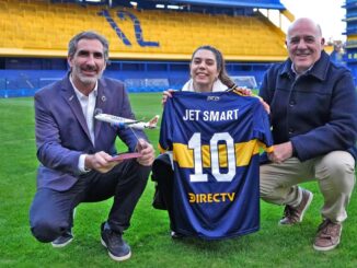 Directivos de JetSMART y Boca Juniors posando en el campo de juego de La Bombonera, sosteniendo una camiseta del club y un modelo a escala de un avión comercial.