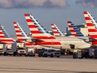 Flota de aeronaves de American Airlines estacionadas en plataforma con vehículos de asistencia en tierra.
