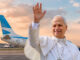 El Papa León XIV saludando en primer plano con un avión Boeing 737 de Aerolíneas Argentinas en la plataforma aeroportuaria de fondo.
