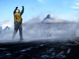Un oficial de cubierta de la Armada de EE. UU. realiza señales de operaciones en vuelo junto a un concepto de caza avanzado.
