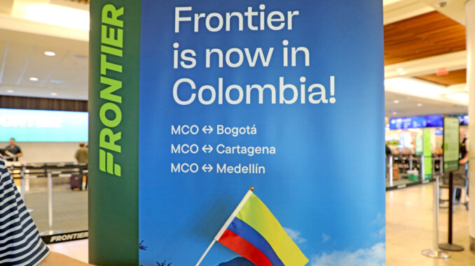 Cartel promocional de Frontier Airlines en el aeropuerto de Orlando anunciando sus nuevas rutas hacia Colombia.