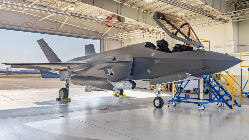 Caza de quinta generación F-35A de la Fuerza Aérea Alemana estacionado dentro de un hangar con la cúpula de la cabina abierta.