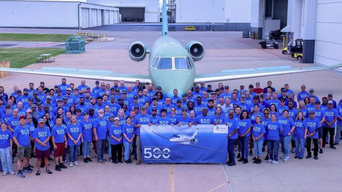 Grupo de empleados de Textron Aviation celebrando frente al jet de negocios Cessna Citation Latitude número 500 en la planta de ensamblaje final.