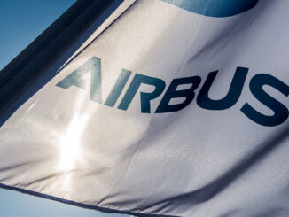 Bandera blanca con el logotipo corporativo azul de Airbus ondeando al viento bajo un cielo despejado.