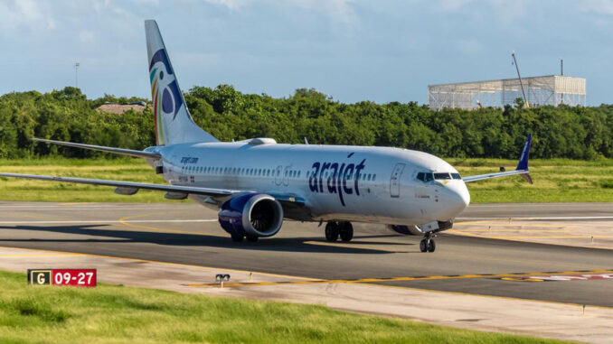 Avión comercial Boeing 737 MAX de la aerolínea dominicana Arajet rodando por la pista de un aeropuerto durante el día.