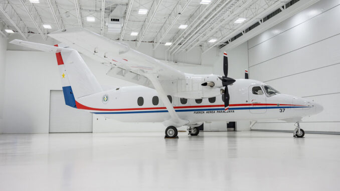 Vista lateral del avión bimotor turbohélice Cessna SkyCourier con el esquema de pintura oficial y los emblemas de la Fuerza Aérea Paraguaya, estacionado dentro de un hangar.